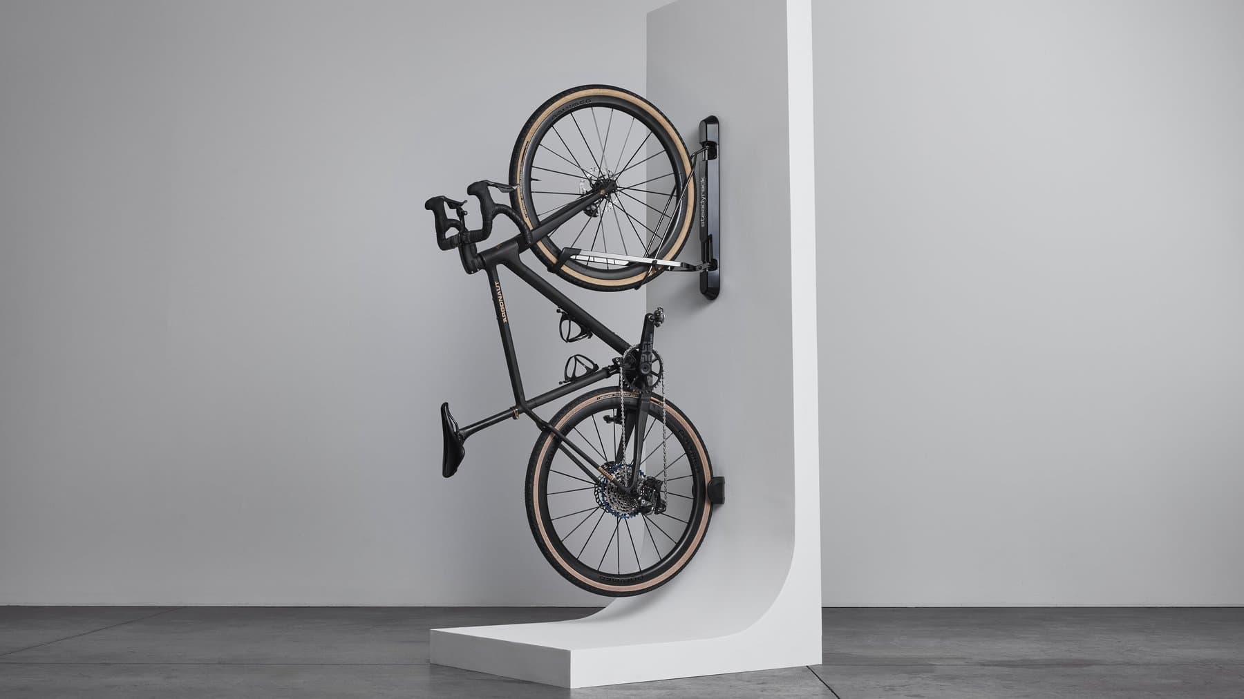 A gravel bike stored vertically on a wall-mounted Steadyrack ProFlex rack, studio shot