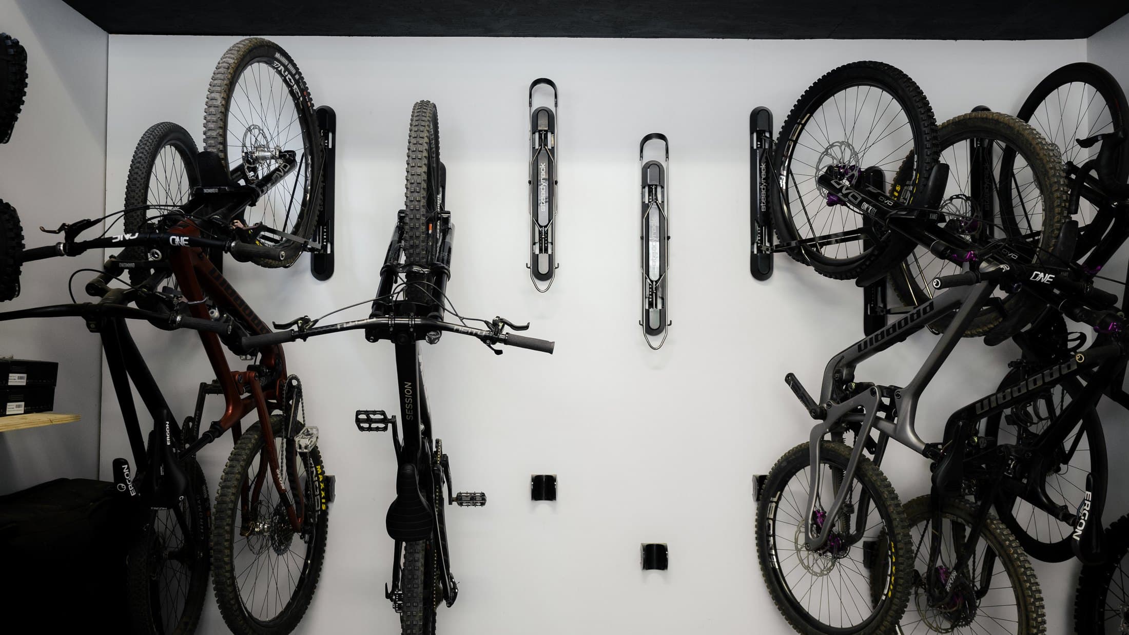 A workshop wall of mountain bikes stored vertically on Steadyrack racks, with two racks left empty